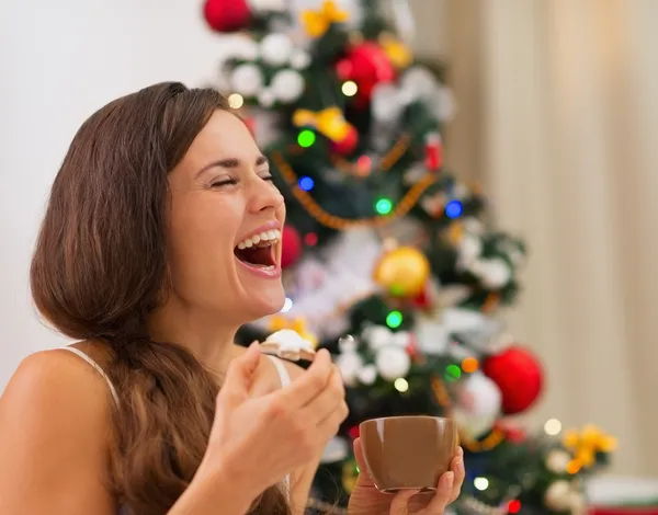 Mujer joven sonriente en pijama comiendo galletas con chocolate caliente —  Fotos de Stock