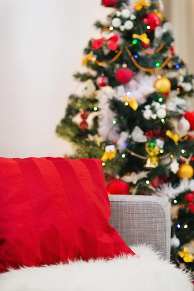 Primer plano en sofá con almohada roja frente al árbol de Navidad — Foto de Stock