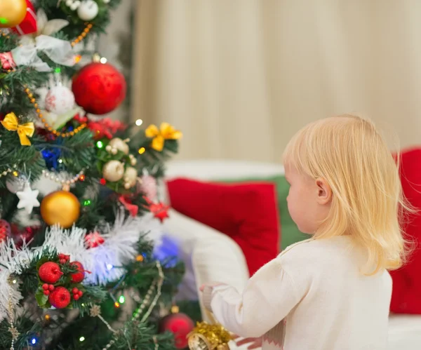 Baby schmückt Weihnachtsbaum. Rückansicht lizenzfreie Stockfotos