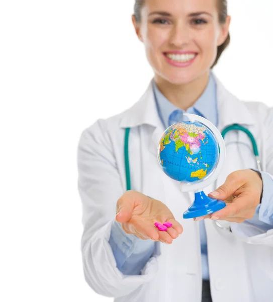 Zbliżenie na uśmiechający się lekarza kobieta gospodarstwa pigułki i świecie — Zdjęcie stockowe