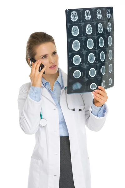 Жінка лікар кажучи стільниковий телефон і дивлячись на МРТ — стокове фото