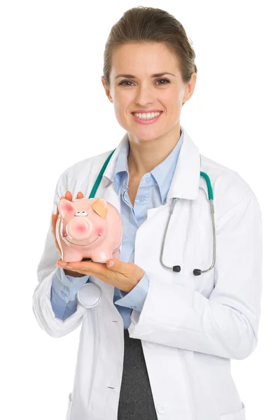 Sorrindo médico mulher segurando porquinho banco — Fotografia de Stock