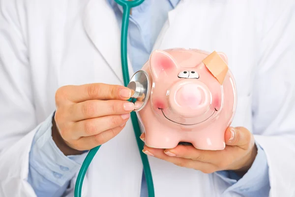 Nahaufnahme auf Arzt hört Sparschwein mit Stethoskop — Stockfoto