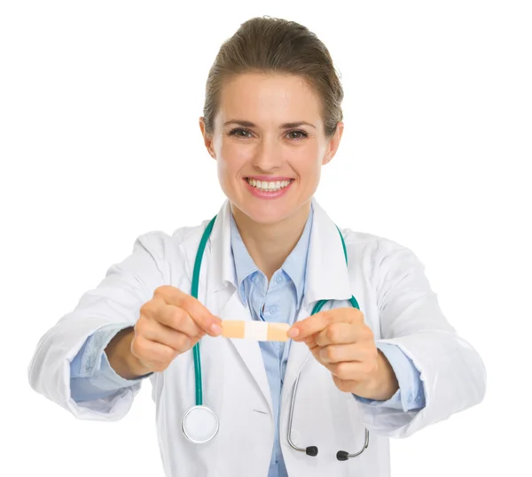 Smiling medical doctor woman reaches out with plaster — Stock Photo, Image