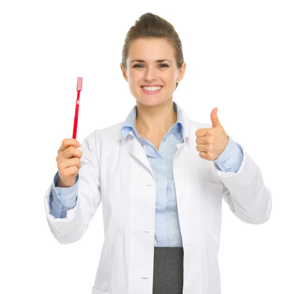 Smiling medical doctor woman showing toothbrush and thumbs up — Stock Photo, Image