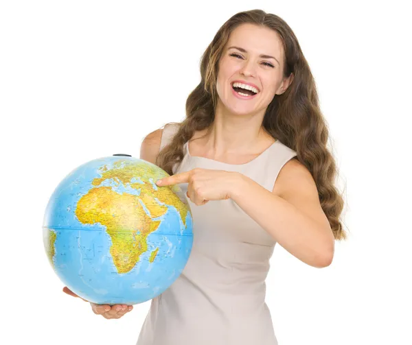 Souriante jeune femme pointant du doigt le globe — Photo