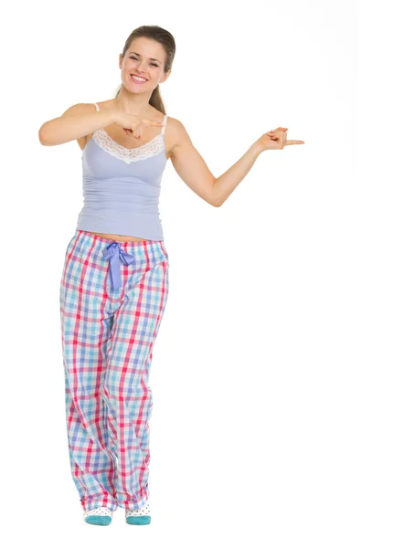 Young woman in pajamas pointing on copy space — Stock Photo, Image