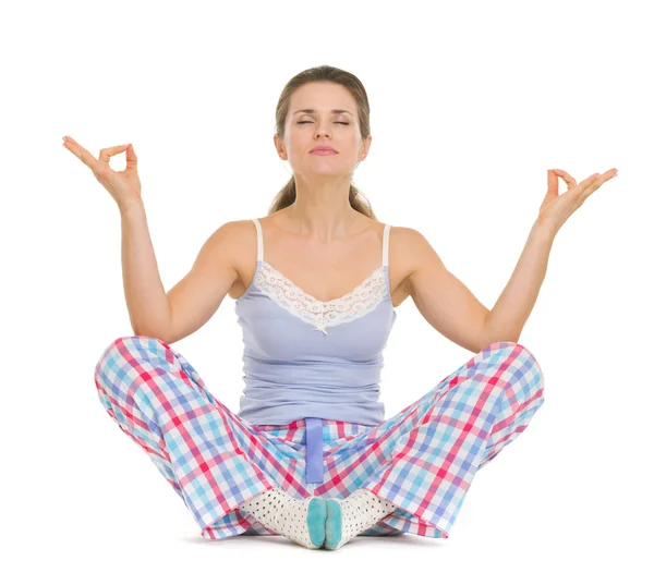 Mujer joven en pijama sentada en el suelo y meditando —  Fotos de Stock