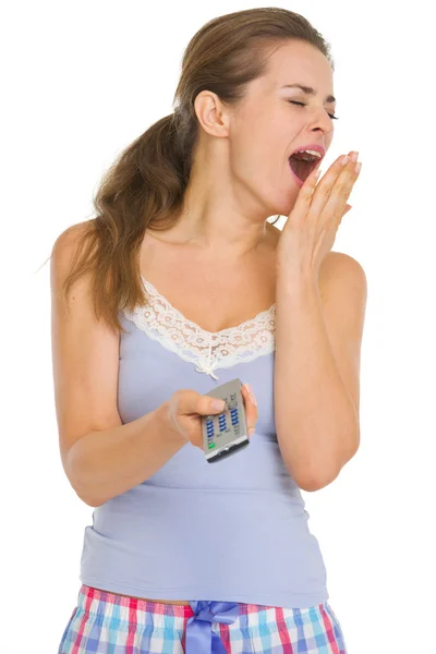 Young woman in pajamas with TV remote control yawing — Stock Photo, Image
