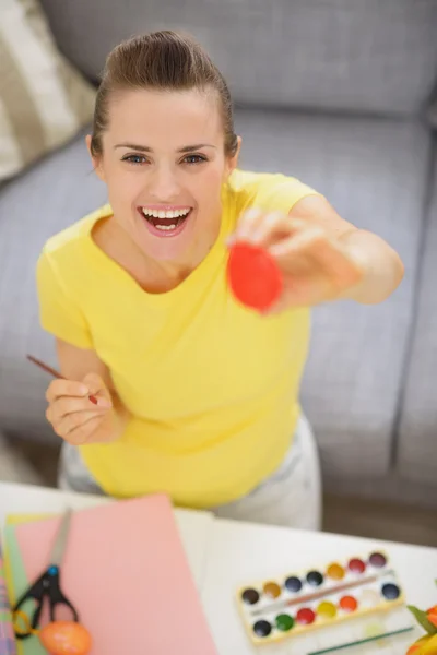 Smiling young woman showing Easter red egg — Stock Photo, Image