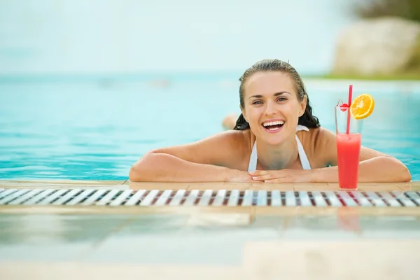 Mujer joven relajándose en la piscina con cóctel — Foto de Stock