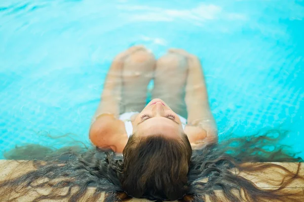 Mladá žena relaxuje v bazénu — Stock fotografie