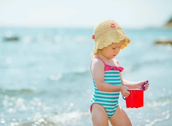 Baby playing with pail near sea — Stock Photo, Image