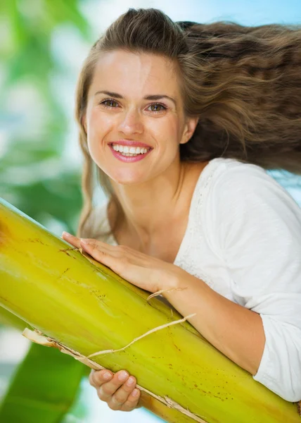 Portret van gelukkige jonge vrouw leunend op tropische palm — Stockfoto