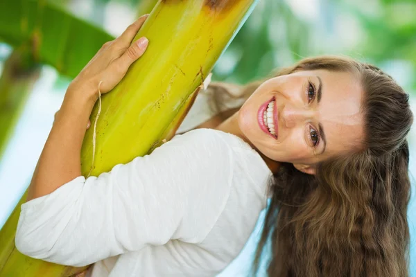 Retrato de uma jovem sorridente apoiada na palma tropical — Fotografia de Stock