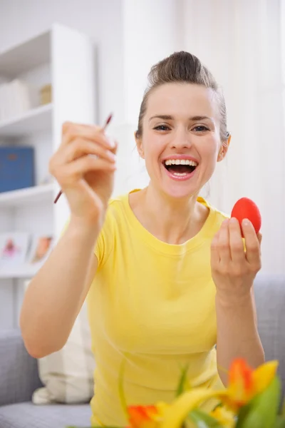 Счастливая молодая женщина рисует пасхальные яйца — стоковое фото