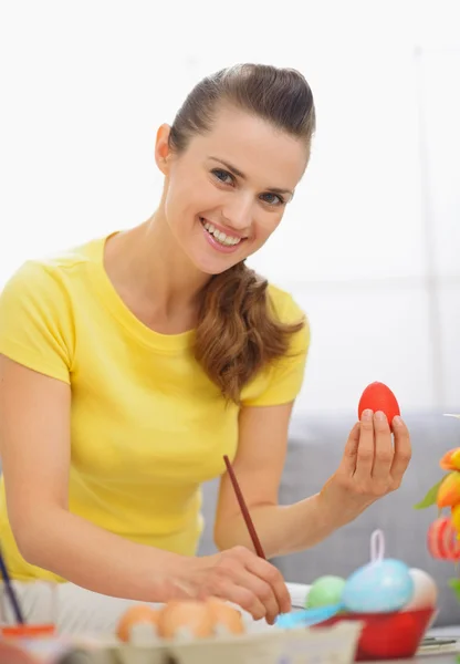 Gülümseyen genç kadın kırmızı yumurta Paskalya hazırlanıyor — Stok fotoğraf