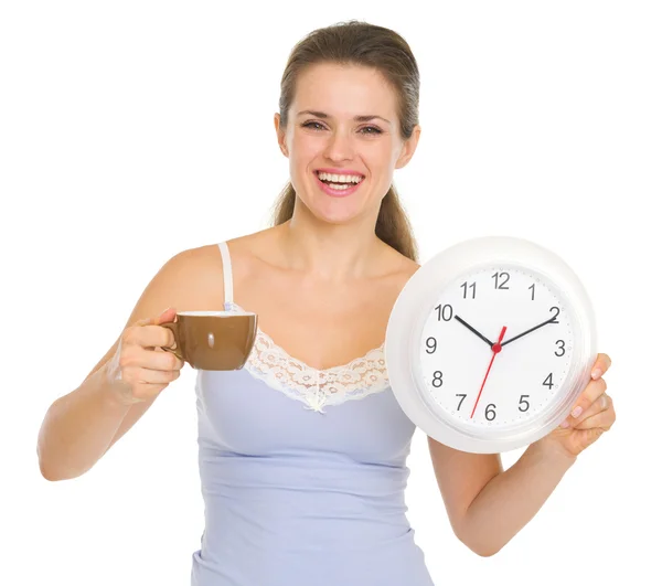 Young woman in pajamas with cup of coffee and clock Royalty Free Stock Images