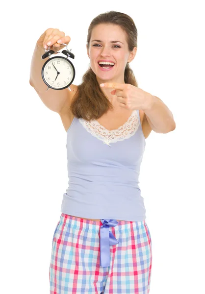 Jonge vrouw in pyjama's op zoek op alarm klok Stockafbeelding