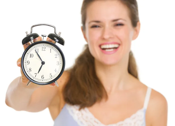 Young woman in pajamas looking on alarm clock Stock Picture