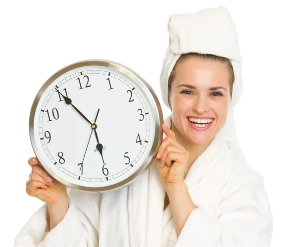 Young woman in bathrobe showing clock and thumbs up Stock Image