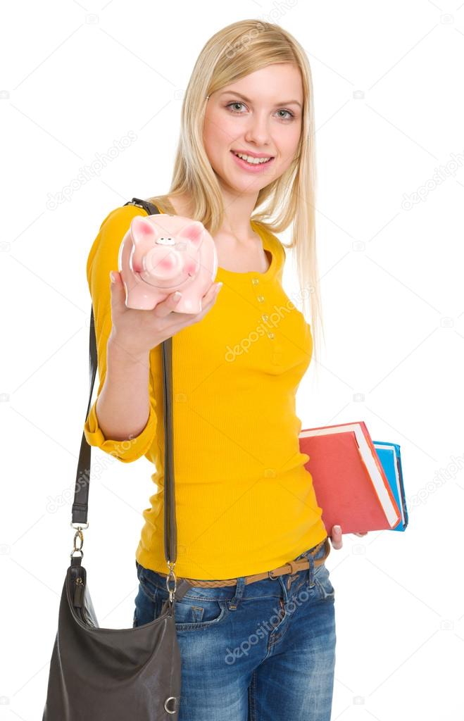 Happy student girl showing piggy bank