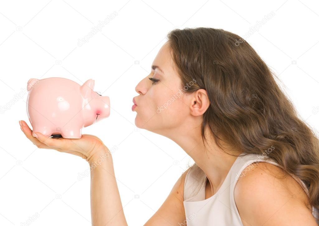 Young woman kissing piggy bank
