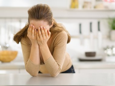 Stressed young woman in kitchen clipart