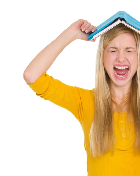 Menina estudante irritado com livro sobre a cabeça — Fotografia de Stock