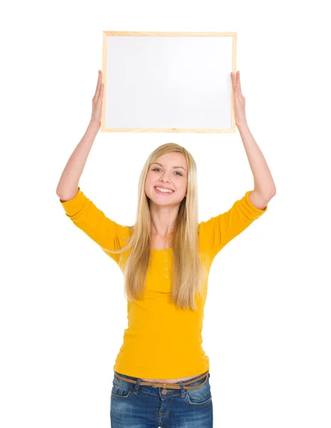 Happy student girl holding blank board over head — Stock Photo, Image