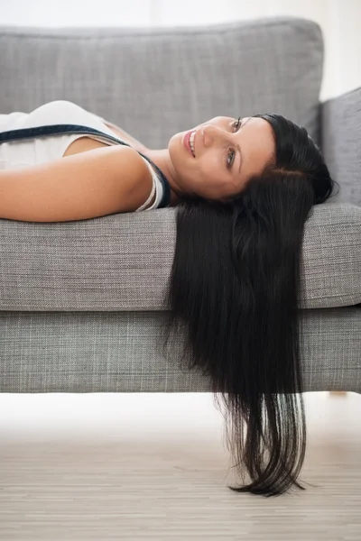 Boldog lány fektetése a kanapéra a nappaliban — Stock Fotó