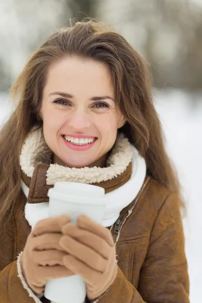 Happy young woman with hot beverage in winter outdoors — Stock Photo, Image