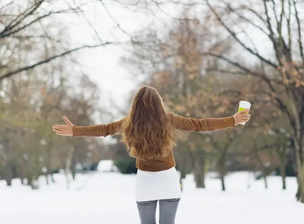 Mujer joven con bebida caliente en el parque de invierno. Vista trasera —  Fotos de Stock