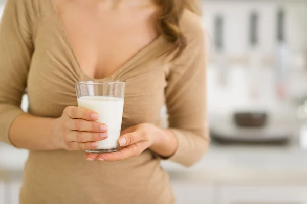 Gros plan sur verre de lait en main de la jeune femme dans la cuisine — Photo