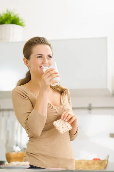 Mujer joven comiendo pan crujiente con leche — Foto de Stock