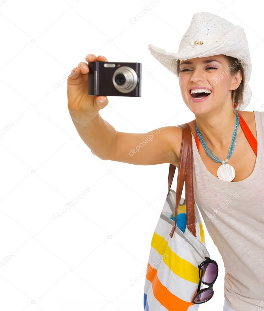 Happy young beach woman in hat taking photo