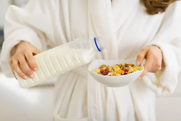 Primer plano de la mujer vertiendo leche en el plato con harina de avena — Foto de Stock