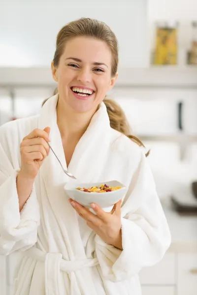 Glückliche junge Frau im Bademantel isst gesundes Frühstück — Stockfoto