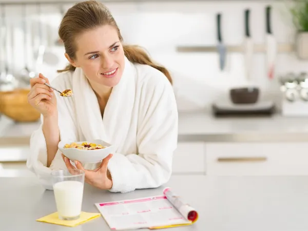 Nachdenkliche junge Frau im Bademantel frühstückt in Küche — Stockfoto