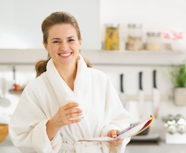 Feliz joven en albornoz con vaso de leche y revista — Foto de Stock