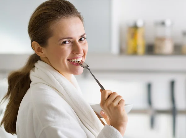 Portrait of young woman in bathrobe eating breakfast in morning — Stock Photo, Image