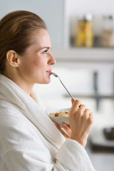 Junge Frau im Bademantel frühstückt morgens — Stockfoto