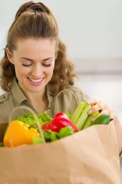 Heureuse jeune femme au foyer examine les achats après les courses en cuisine — Photo