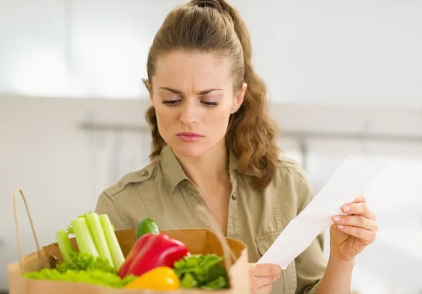 Concerned young housewife examines check after shopping — Stock Photo, Image