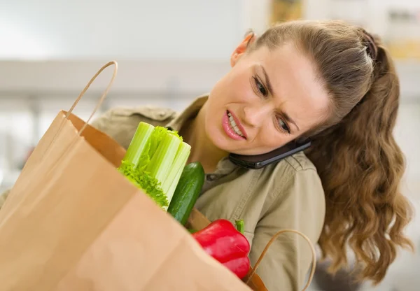 Preoccupato giovane casalinga con grande shopping bag parlando mobile p — Foto Stock