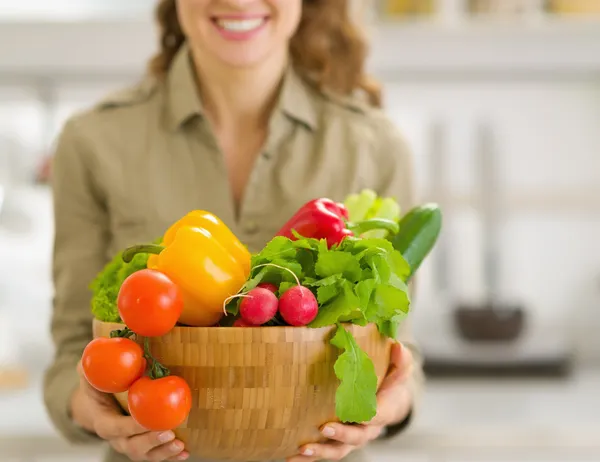 Närbild på tallrik färska grönsaker i handen i ung hemmafru — Stockfoto