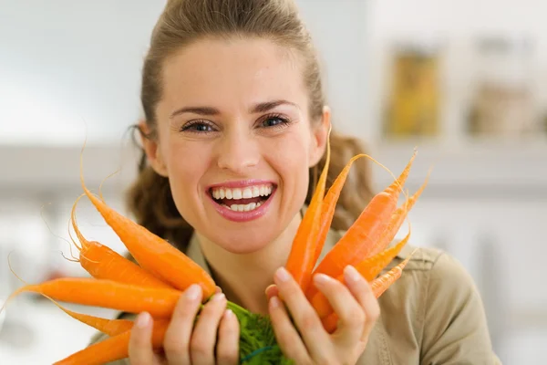 Jeune femme souriante montrant des carottes fraîches — Photo