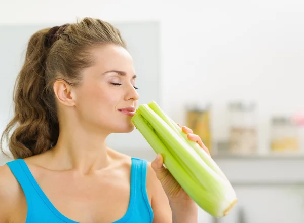 Young woman smelling celery in kitchen — Stock Photo, Image