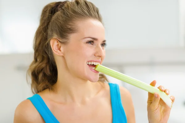 Счастливая молодая женщина кусает сельдерей на кухне — стоковое фото