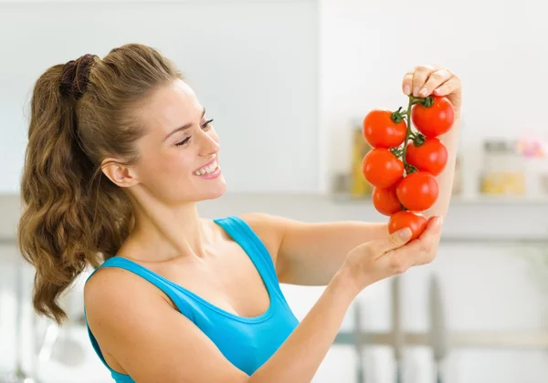 Jovem feliz segurando um monte de tomate na cozinha — Fotografia de Stock